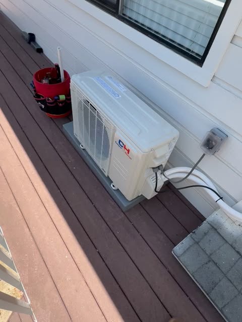 Mini-split outdoor unit mounted on a deck beside a home